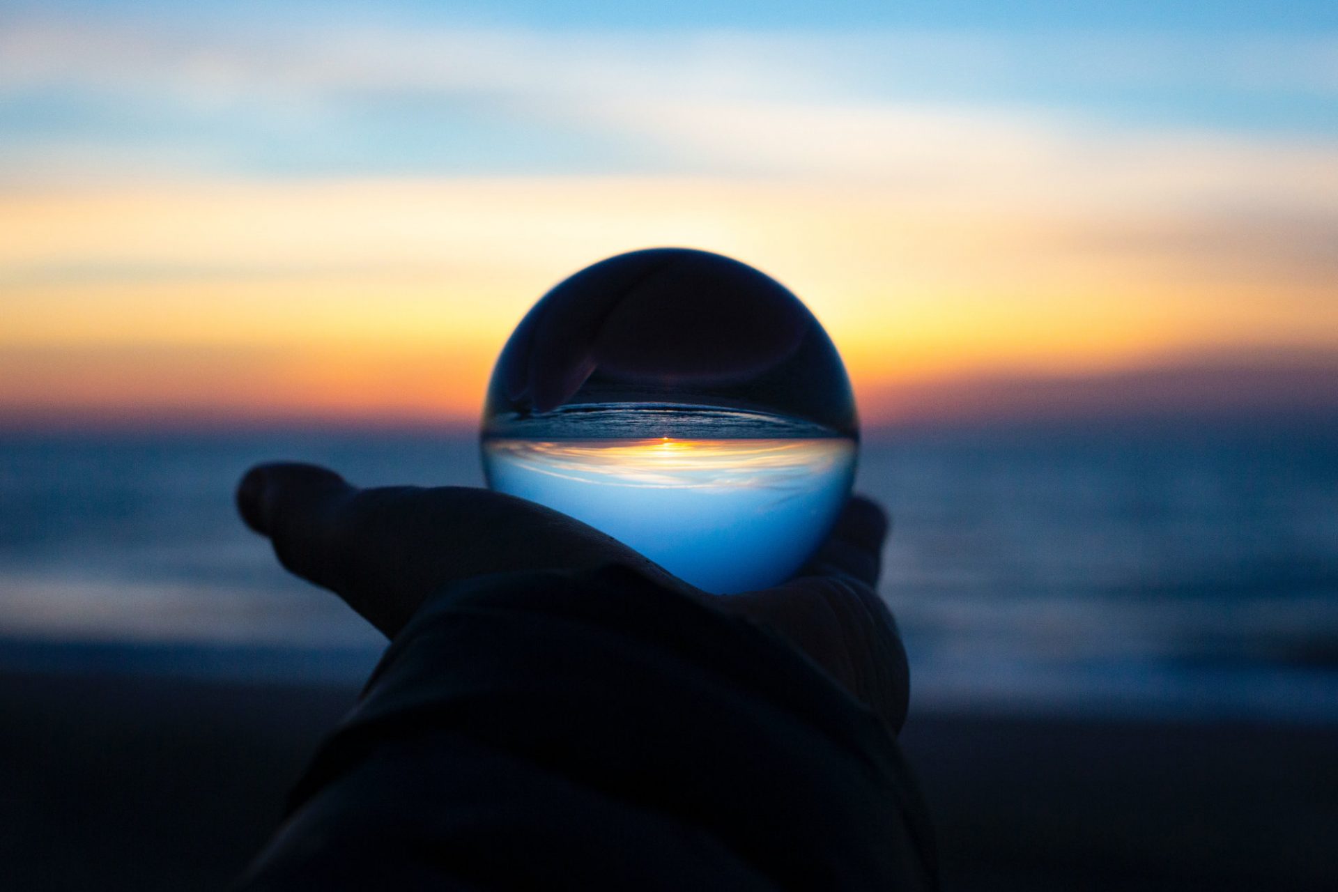 A glass orb held in a hand reflects the upside down world